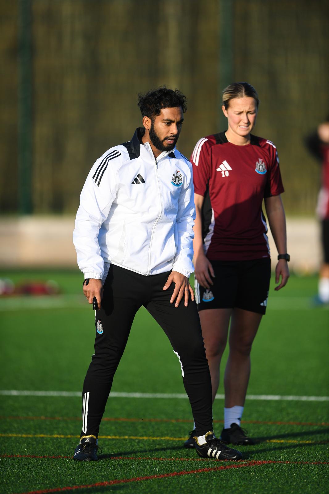 Coach working with a player on the pitch
